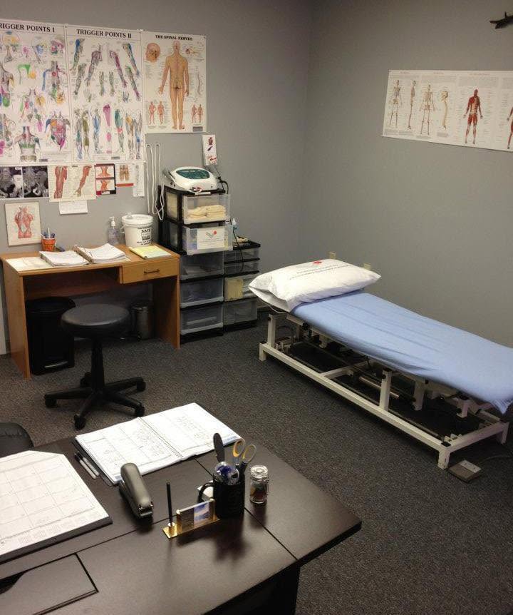 The treatment room at Beechwood Physiotherapy, with a treatment bed, desk, and anatomy charts